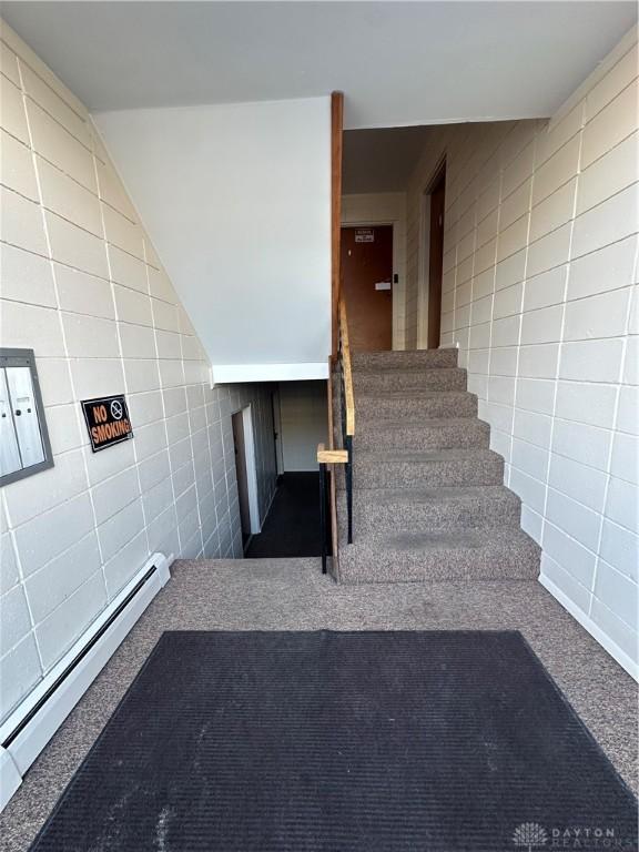 stairway with a baseboard radiator, carpet, and lofted ceiling