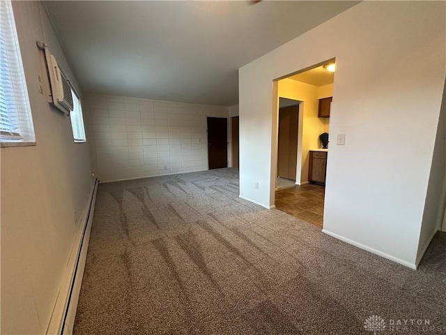 carpeted empty room featuring a wall mounted AC and a baseboard heating unit