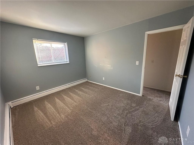 spare room with dark colored carpet and a baseboard radiator