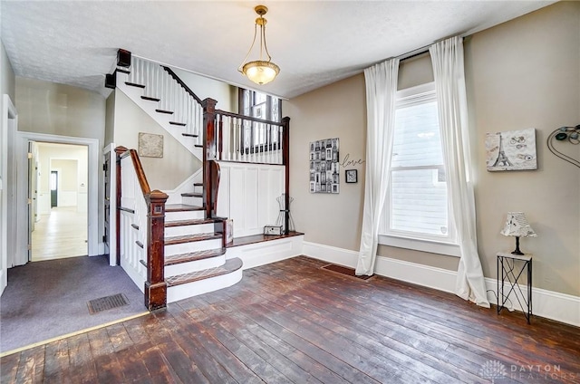 foyer entrance with dark wood-type flooring, plenty of natural light, and a textured ceiling