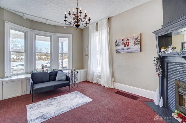 sitting room with dark colored carpet, a healthy amount of sunlight, and a textured ceiling