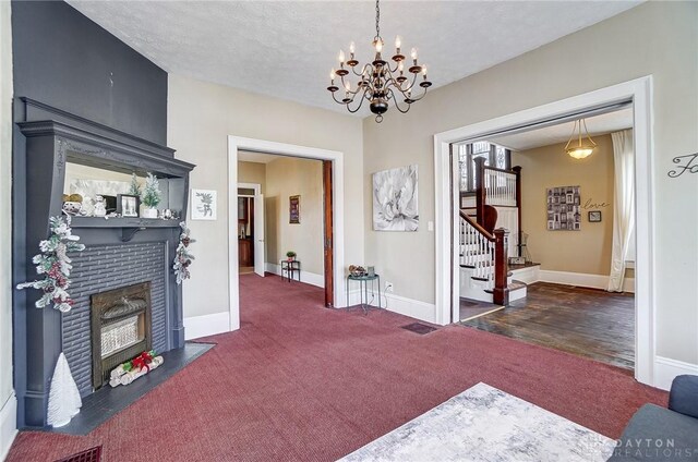 carpeted foyer entrance featuring a textured ceiling and a chandelier