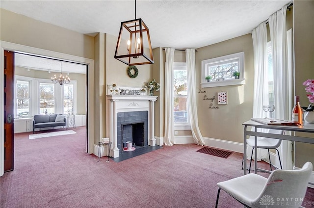 carpeted living room with a tiled fireplace, an inviting chandelier, and a textured ceiling