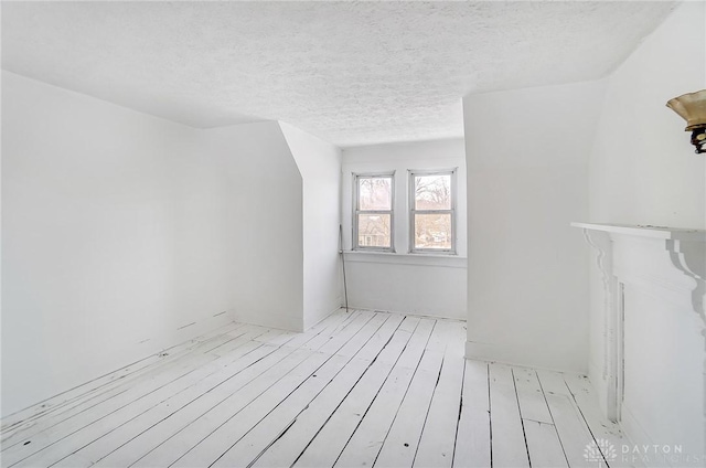 additional living space with light hardwood / wood-style floors and a textured ceiling