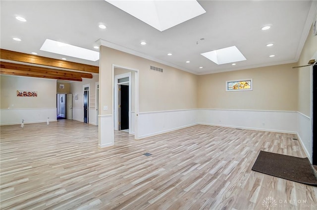 unfurnished room with light hardwood / wood-style floors, crown molding, and a skylight