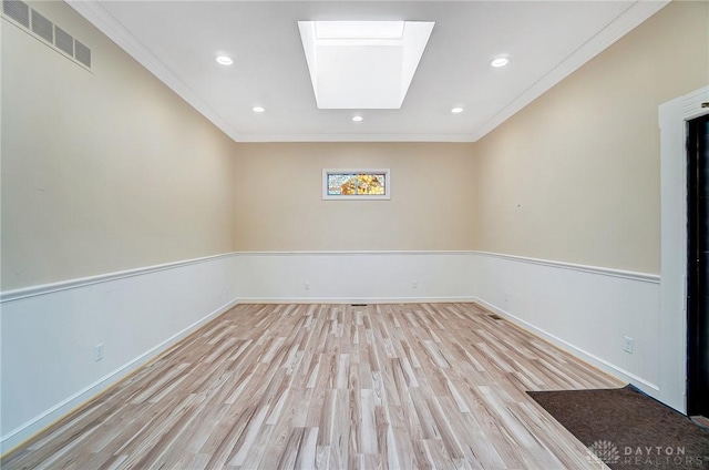 unfurnished room featuring light hardwood / wood-style floors, a skylight, and ornamental molding