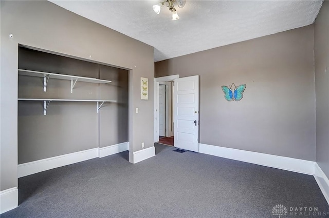 unfurnished bedroom with dark carpet, a closet, and a textured ceiling