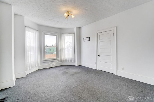 carpeted spare room with a textured ceiling