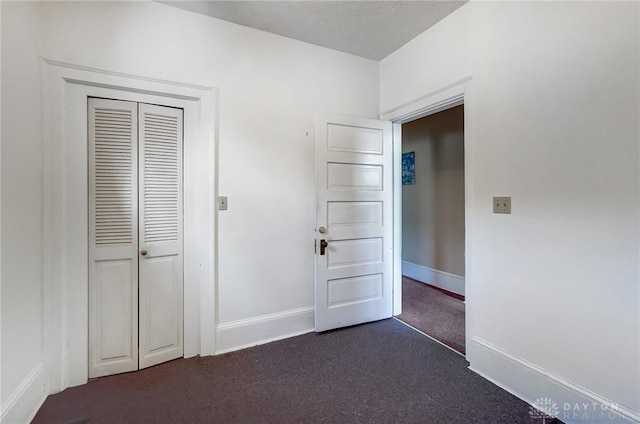 unfurnished bedroom with a closet and dark colored carpet