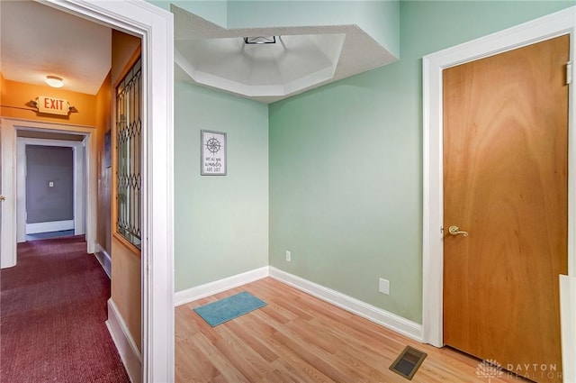 hallway featuring wood-type flooring and a tray ceiling