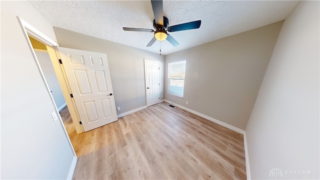 unfurnished bedroom with light wood-type flooring, ceiling fan, and a textured ceiling