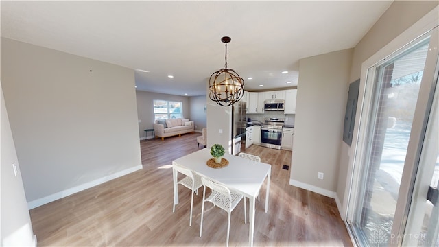 dining space featuring light wood-type flooring and a chandelier