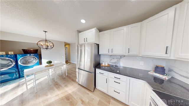 kitchen featuring hanging light fixtures, independent washer and dryer, backsplash, white cabinetry, and stainless steel refrigerator