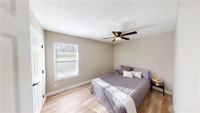 bedroom featuring ceiling fan, light hardwood / wood-style floors, and a textured ceiling