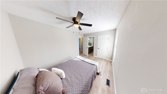 bedroom featuring ceiling fan, light hardwood / wood-style floors, and a textured ceiling