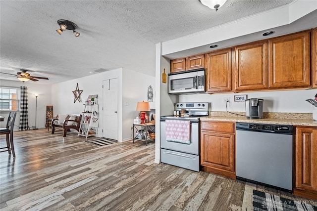 kitchen featuring ceiling fan, dark wood-type flooring, a textured ceiling, and stainless steel appliances