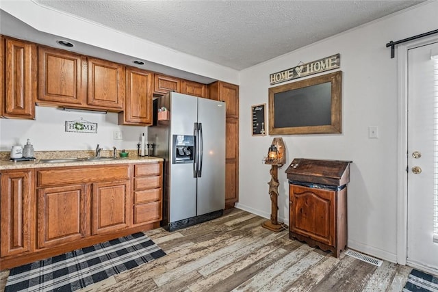 kitchen featuring stainless steel fridge with ice dispenser, dark hardwood / wood-style flooring, a textured ceiling, and sink