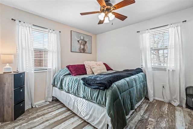 bedroom with ceiling fan, multiple windows, and hardwood / wood-style flooring