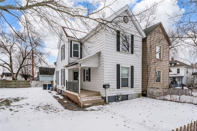 view of snowy exterior with fence and covered porch