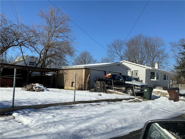 view of snowy exterior with a garage and a carport