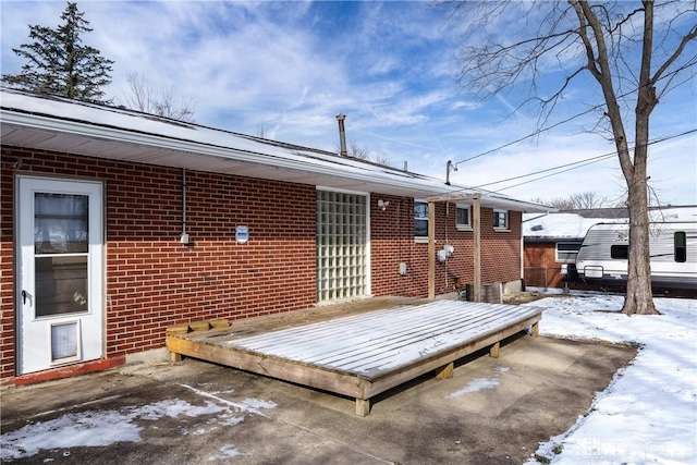 snow covered back of property with a deck