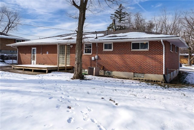 snow covered house with a wooden deck and central AC