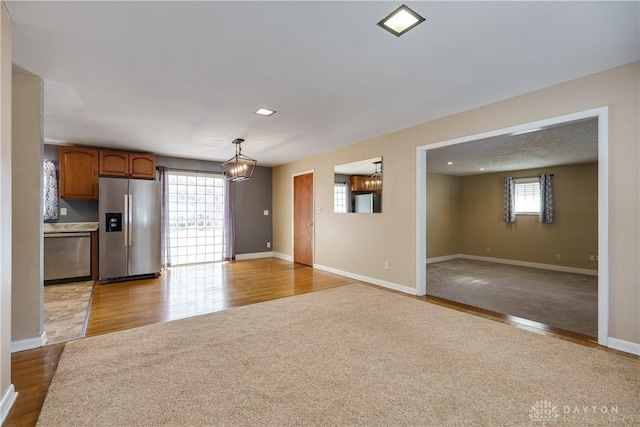 unfurnished living room featuring light hardwood / wood-style flooring, plenty of natural light, and an inviting chandelier