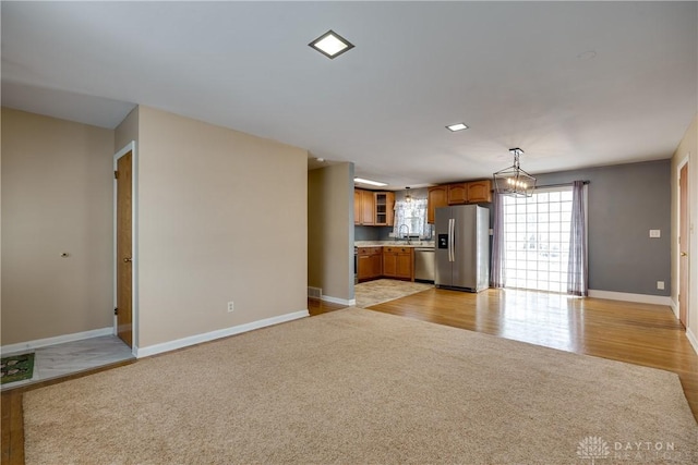 unfurnished living room featuring an inviting chandelier and light hardwood / wood-style floors