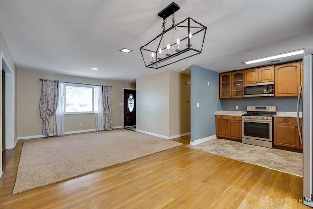 kitchen featuring light wood-type flooring, stainless steel appliances, hanging light fixtures, and an inviting chandelier