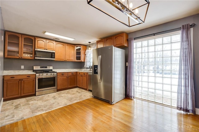 kitchen with light wood-type flooring, stainless steel appliances, pendant lighting, and sink