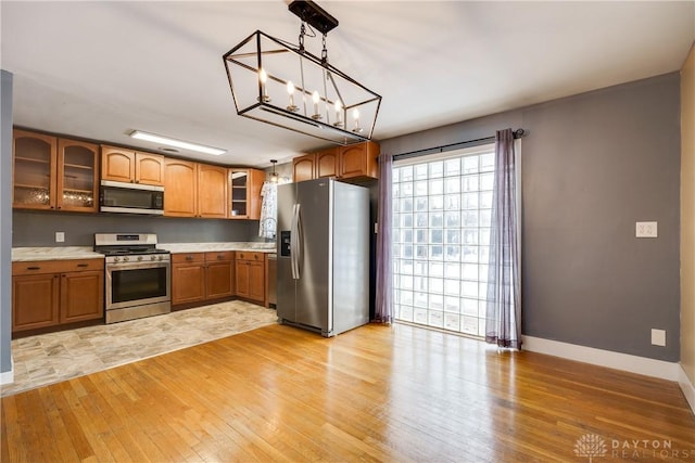 kitchen with light hardwood / wood-style floors, sink, hanging light fixtures, and appliances with stainless steel finishes