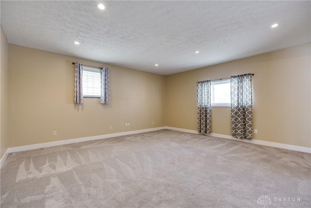 carpeted empty room featuring plenty of natural light and a textured ceiling