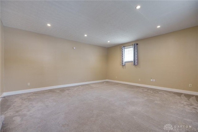 unfurnished room with light colored carpet and a textured ceiling