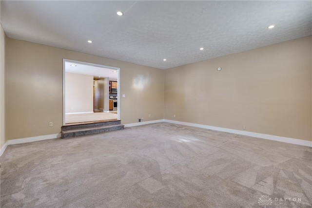 unfurnished room with carpet and a textured ceiling