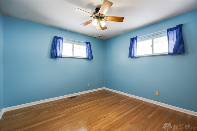 unfurnished room with ceiling fan, a wealth of natural light, and hardwood / wood-style floors