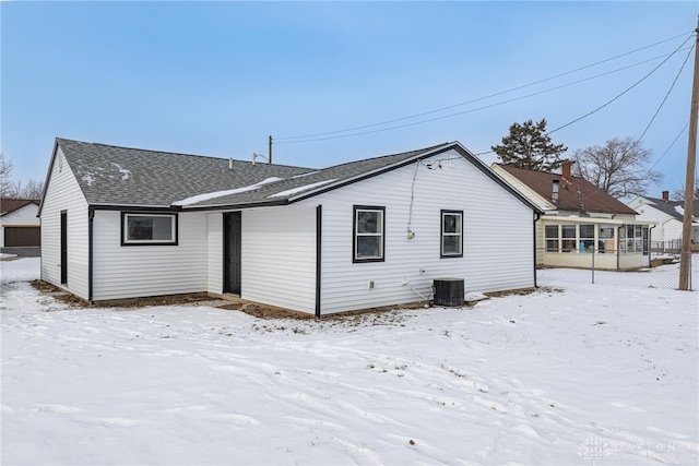 snow covered back of property featuring central AC