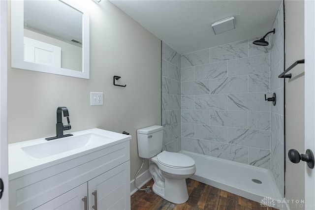 bathroom featuring hardwood / wood-style floors, toilet, vanity, and tiled shower