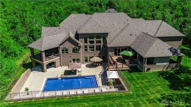 rear view of house featuring a patio area, a fenced in pool, and a yard