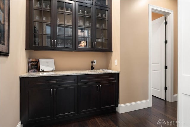 bar featuring sink, dark wood-type flooring, and light stone countertops