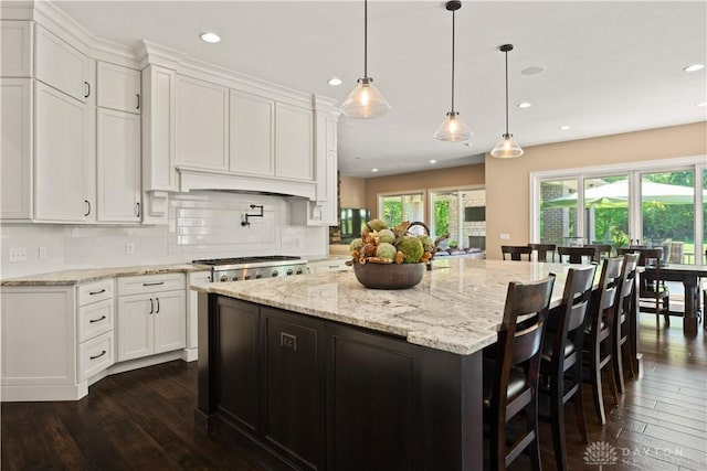 kitchen featuring pendant lighting, white cabinets, a center island, dark hardwood / wood-style flooring, and stainless steel gas cooktop