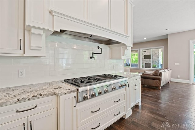 kitchen featuring decorative backsplash, premium range hood, light stone counters, and stainless steel gas stovetop