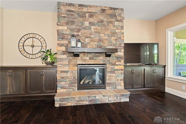 unfurnished living room with dark hardwood / wood-style floors and a stone fireplace