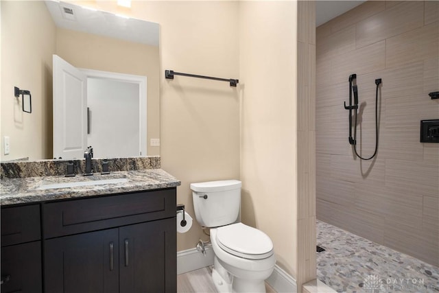 bathroom with toilet, vanity, and tiled shower