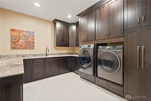 laundry area with washing machine and dryer, cabinets, and sink