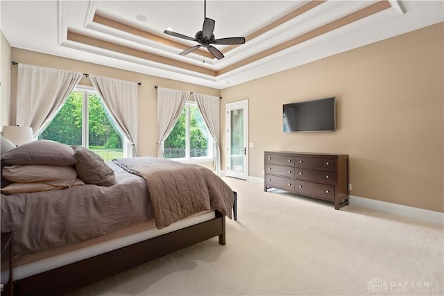 carpeted bedroom featuring access to outside, ceiling fan, and a raised ceiling