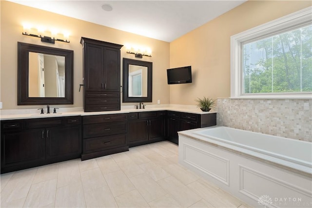 bathroom with a washtub, vanity, and tile patterned flooring