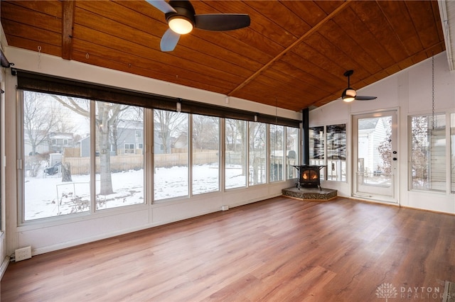 unfurnished sunroom with wood ceiling, ceiling fan, lofted ceiling, and a wood stove