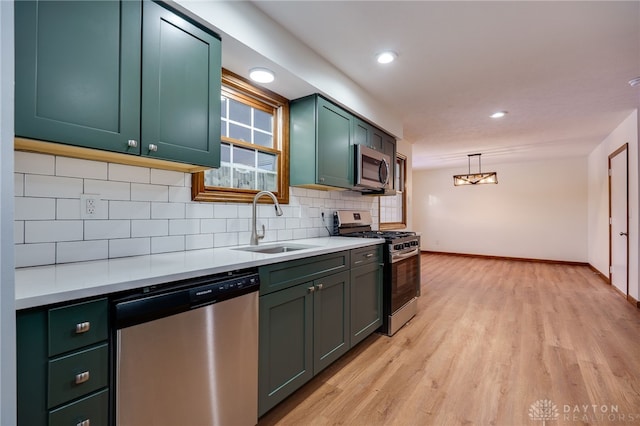 kitchen with sink, tasteful backsplash, green cabinetry, decorative light fixtures, and appliances with stainless steel finishes