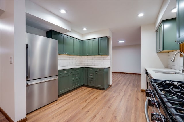 kitchen featuring green cabinets, stainless steel appliances, sink, and backsplash