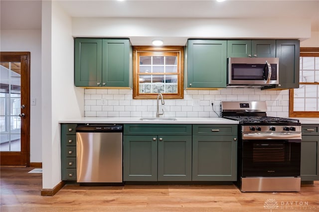 kitchen with green cabinetry, appliances with stainless steel finishes, light hardwood / wood-style floors, and sink